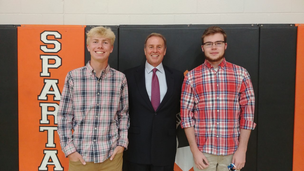 one man in a suit, with two boys wearing flannel